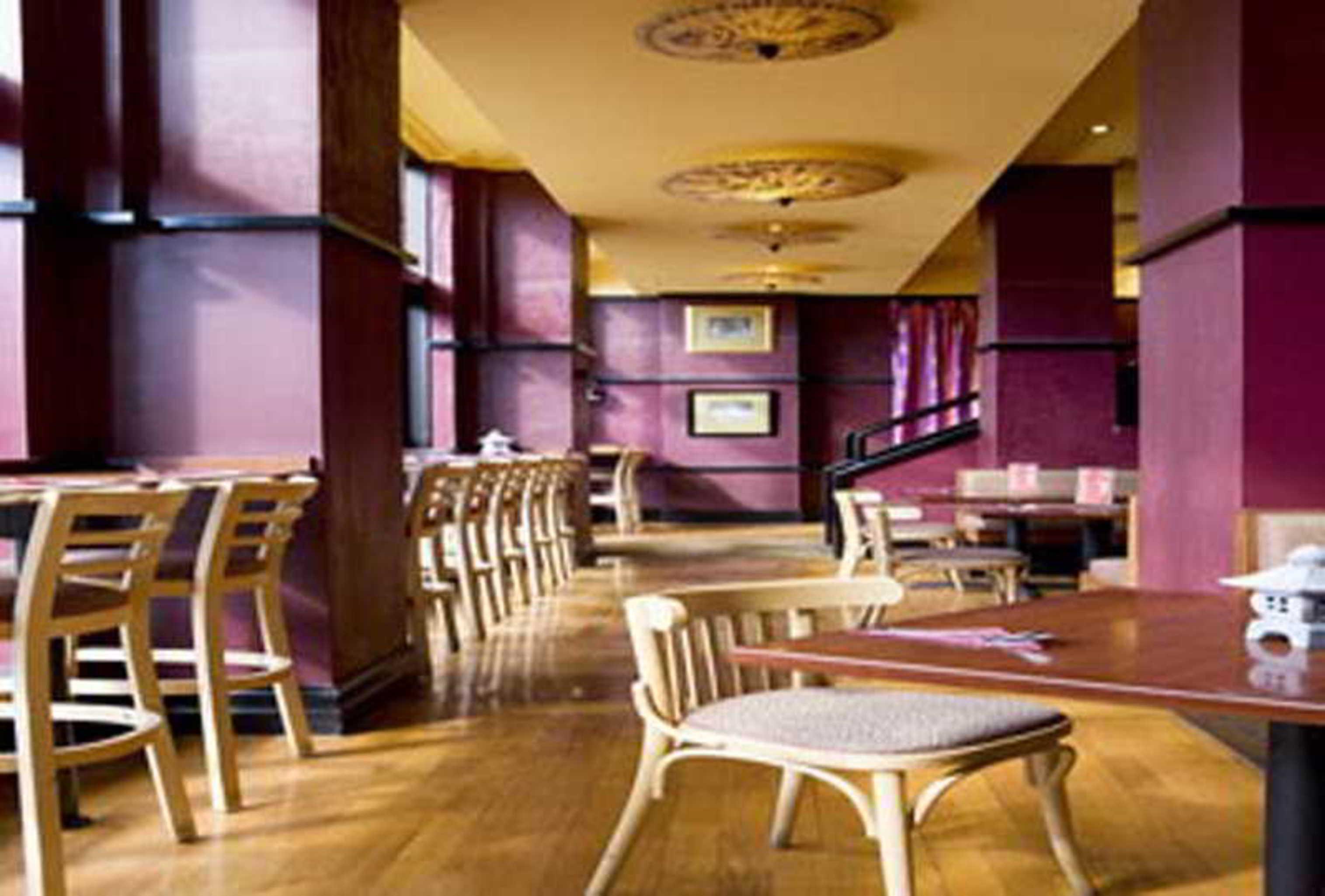 Готель Stamford Grand Adelaide Ґленелґ Екстер'єр фото The photo shows the interior of a restaurant. It features wooden flooring and a warm color palette, primarily using shades of burgundy and gold. There are several wooden chairs arranged around tables, with the seating area appearing spacious and invi