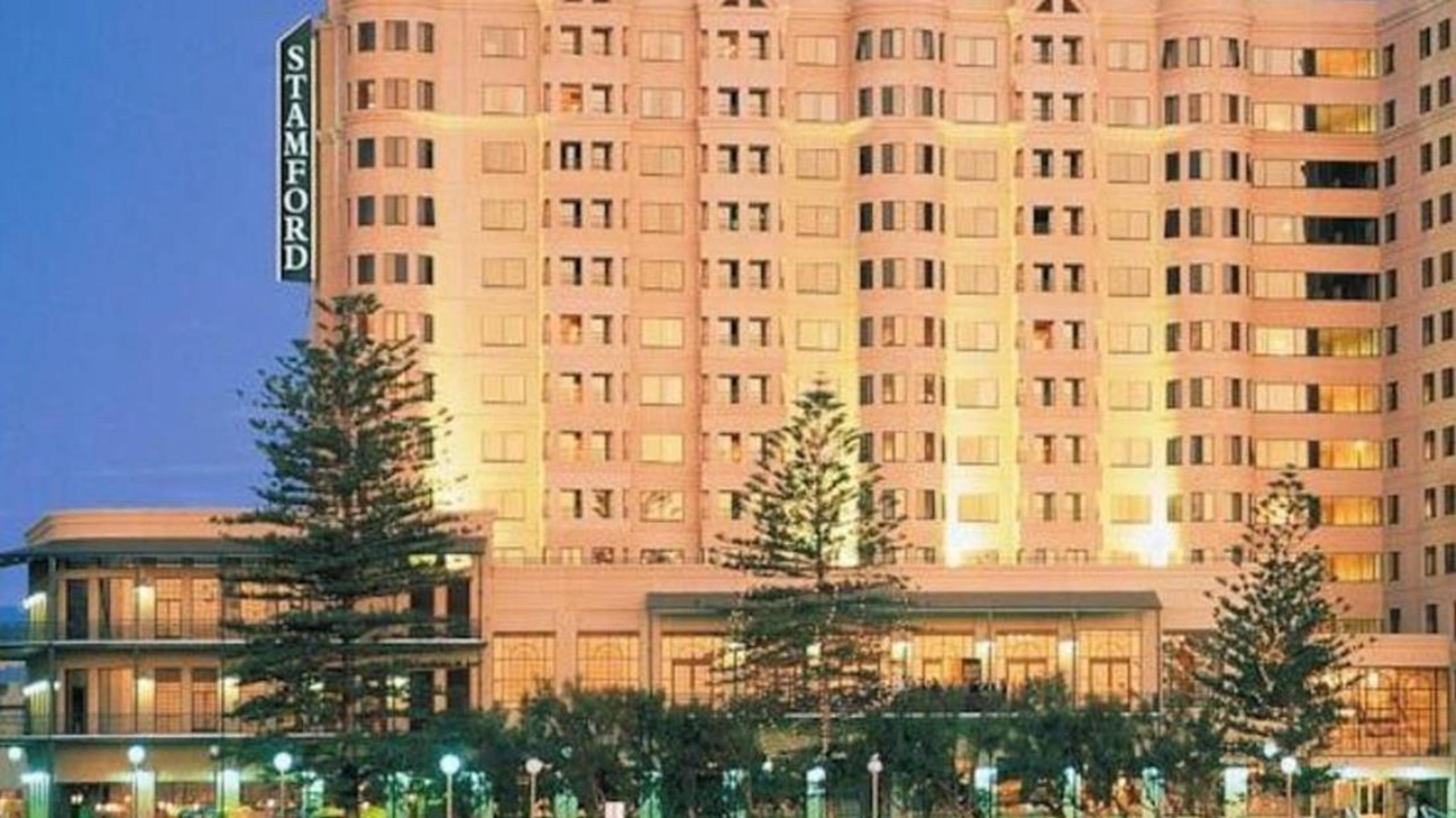 Готель Stamford Grand Adelaide Ґленелґ Екстер'єр фото The photo shows a tall, modern building illuminated at night, likely a hotel, with the name "Stamford" prominently displayed on its side. Surrounding the building are several palm trees and landscaped areas, suggesting a tropical or coastal location.