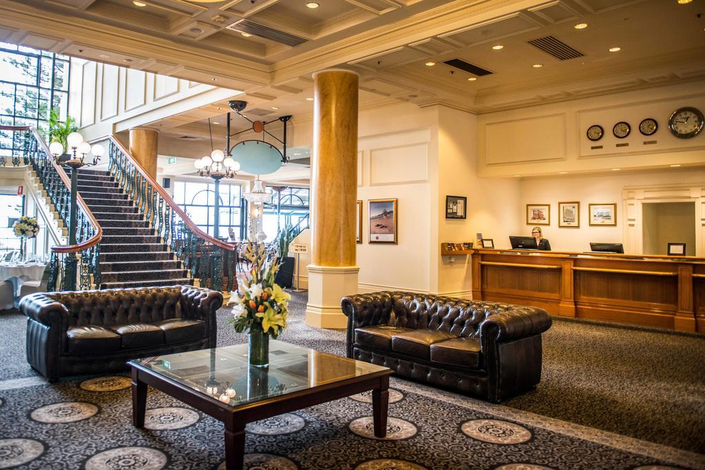 Готель Stamford Grand Adelaide Ґленелґ Екстер'єр фото The photo depicts a hotel lobby featuring a spacious and elegant design. There are two dark leather sofas arranged in front of a glass coffee table, adorned with a floral centerpiece. The lobby has a refined atmosphere, highlighted by large windows t