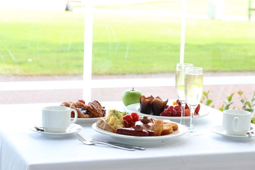 Готель Stamford Grand Adelaide Ґленелґ Екстер'єр фото The photo displays a beautifully arranged breakfast setup on a white tablecloth. In the center, there is a large white plate with a variety of foods, including eggs, sausage, and fresh fruit. Surrounding the plate are a few other food items, such as 